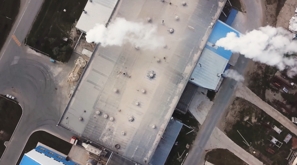 Aerial view of cement production facility with emissions being released from 3 chimneys.